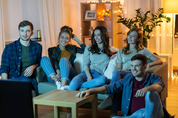 happy friends watching tv at home in evening - Foto, Bild
