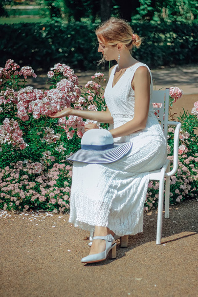 Jeune belle femme en robe blanche dans le jardin vert avec des fleurs ferment en été
 - Photo, image