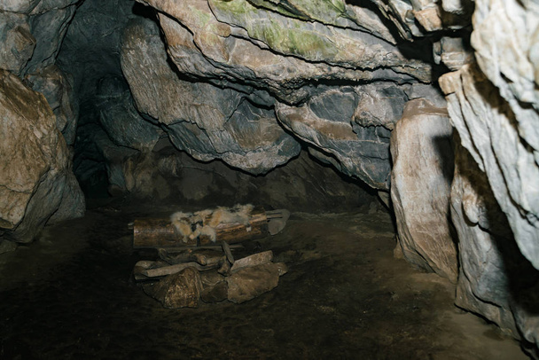 Piękna Jaskinia. Widok z wnętrza ciemnego lochu. Teksturowane ściany jaskini. Obraz tła podziemnego tunelu. Wilgoć wewnątrz jaskini. Mieszkania prymitywnych jaskiniowych ludzi. - Zdjęcie, obraz