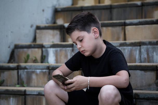 Portret van een trieste tiener jongen op de telefoon die attent op problemen. Pensive tiener. Depressie, tiener depressie, pijn, lijden. - Foto, afbeelding