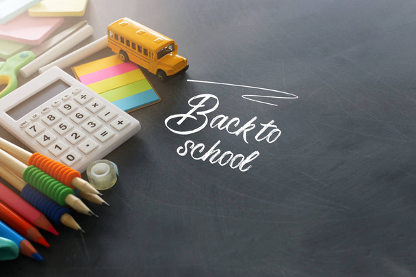 education and back to school concept. stationery and bus over classroom blackboard. top view, flat lay - Foto, afbeelding