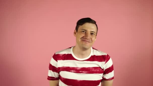 Man smiling and confused standing on pink background - Video