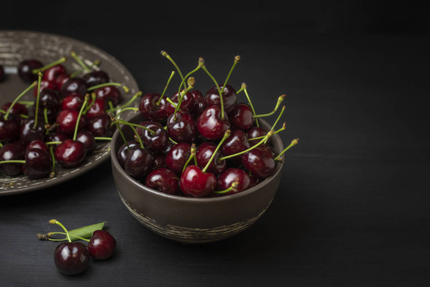 Fresh sweet cherries bowl on black background. Healthy food concept, plant background, natural eco-products, organic food, vegetarian, raw, festival food, art - Photo, image