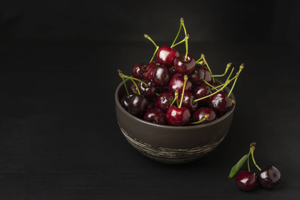 Fresh sweet cherries bowl on black background. Healthy food concept, plant background, natural eco-products, organic food, vegetarian, raw, festival food, art - Photo, Image