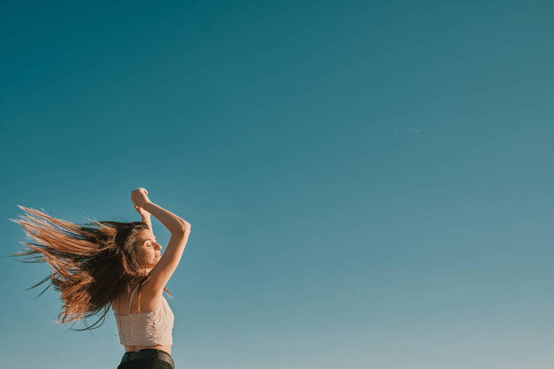 una mujer joven en un día de verano con un cielo azul - espacio negativo
 - Foto, imagen