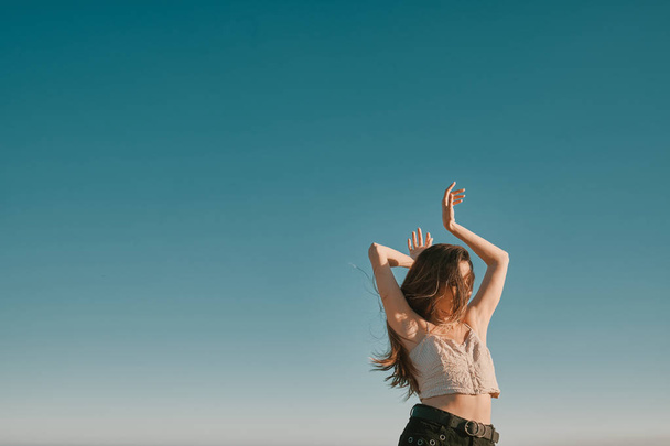 eine junge Frau an einem Sommertag mit blauem Himmel - negativer Raum - Foto, Bild