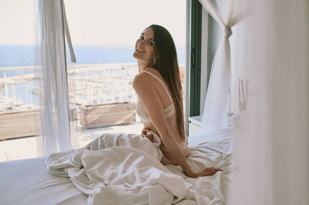 a young model in underwear seated in front of a window - Fotoğraf, Görsel