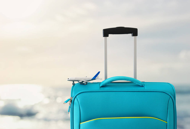 holidays. travel concept. blue suitcase and airplane toy infront of tropical sea background - Fotografie, Obrázek