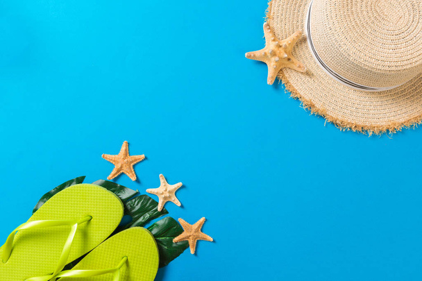 Beach accessories with straw hat and seashells on blue background top view with copy space - Photo, Image