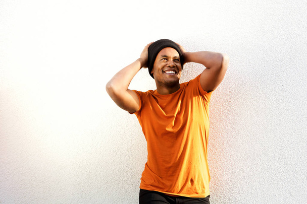 Porträt eines unbeschwerten jungen schwarzen Mannes, der mit den Händen hinter dem Kopf vor weißem Hintergrund lächelt - Foto, Bild