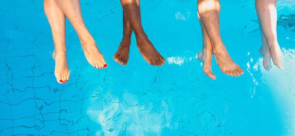 čtyři přátelé (běžní lidé) různé rasy v bazénu za slunečného dne. Strana. Letní. Koncepce dovolené a sportu. - Fotografie, Obrázek