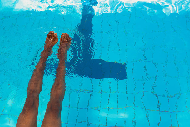 felnőtt afro-amerikai ember lába víz alatt a medencében - Fotó, kép