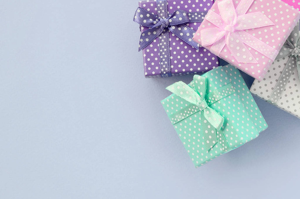 Σωρός από ένα μικρό χρωματιστό κουτιά δώρων με κορδέλες είναι σε ένα βιολετί φόντο - Φωτογραφία, εικόνα