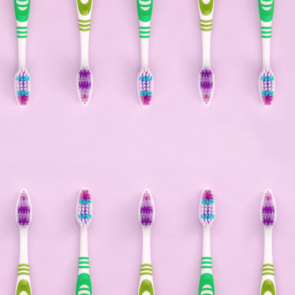 Много зубных щёток лежат на розовом фоне.
 - Фото, изображение