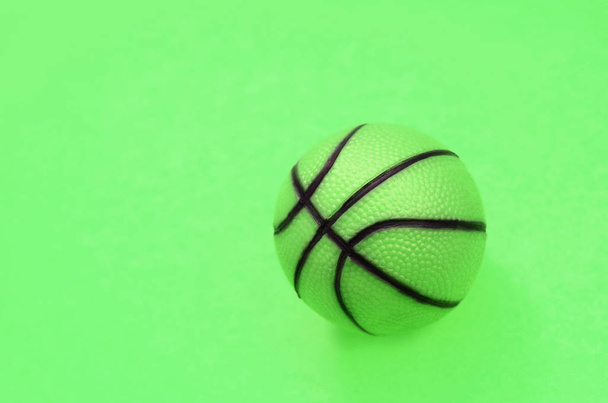 Malá zelená koule pro basketbalovou hru leží na pozadí textury - Fotografie, Obrázek