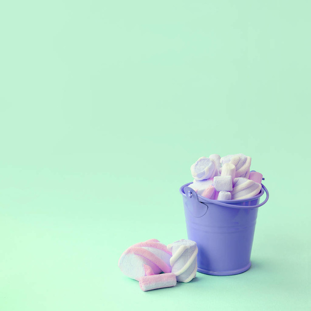 Un cubo de lilas en miniatura lleno de malvavisco se encuentra sobre un fondo verde pastel
 - Foto, Imagen