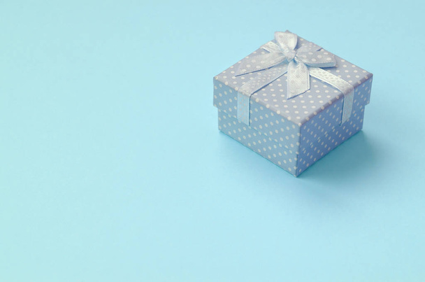 Μικρό μπλε κουτί δώρου βρίσκεται στην υφή φόντο της μόδας παστέλ μπλε χρώμα χαρτί - Φωτογραφία, εικόνα