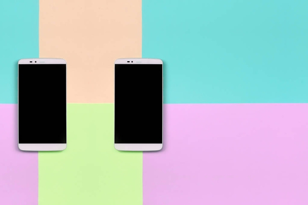 Два сучасних смартфона з чорними екранами на тлі модних пастельних рожевих, синіх, коралових і лайм кольорів
 - Фото, зображення