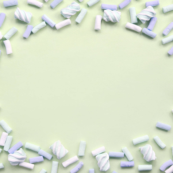 Marshmallow colorido dispuesto sobre fondo de papel de lima. pastel marco texturizado creativo
 - Foto, Imagen