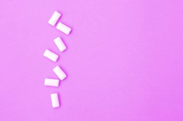 A few chewing gums lie on texture background of fashion pastel purple color paper - Photo, Image