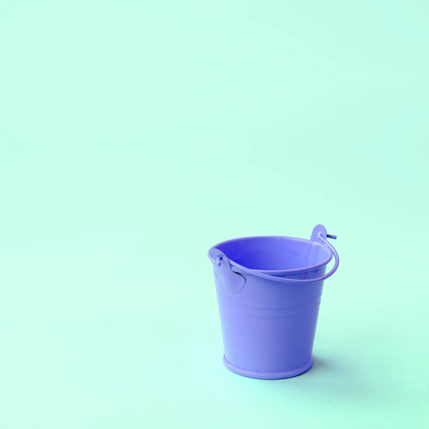 A miniature empty lilac bucket lies on a green pastel background - Fotoğraf, Görsel