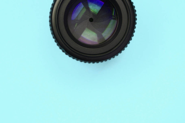 A lente de câmera com uma abertura fechada está no fundo de textura do papel a cores azul pastel de moda
 - Foto, Imagem