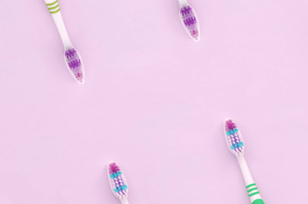 Una gran cantidad de cepillos de dientes se encuentran sobre un fondo rosa pastel
 - Foto, Imagen