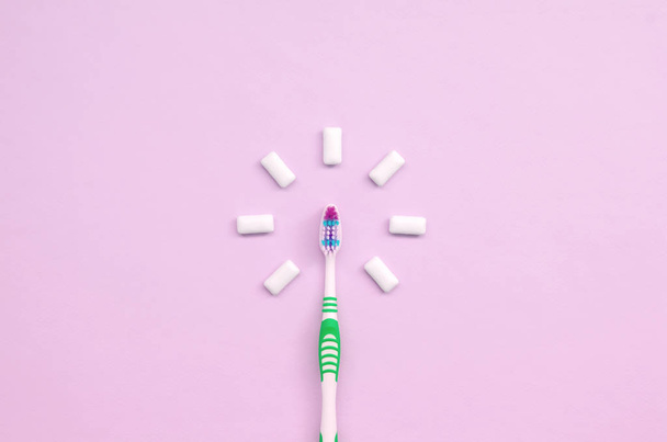 Toothbrush and chewing gums lie on a pastel pink background - Фото, изображение