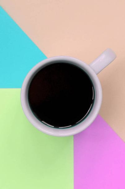 Небольшая белая чашка кофе на фактурном фоне модной бумаги розового, голубого, кораллового и лаймового цветов
 - Фото, изображение