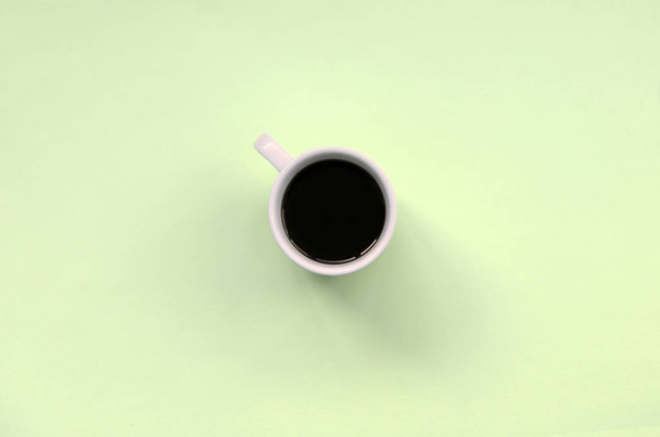 Small white coffee cup on texture background of fashion pastel lime color paper - Photo, Image