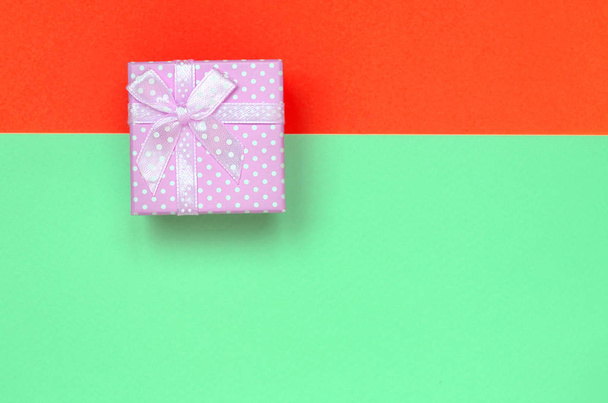Pequeña caja de regalo rosa se encuentran en el fondo de textura de la moda pastel de color turquesa y rojo papel de colores
 - Foto, imagen