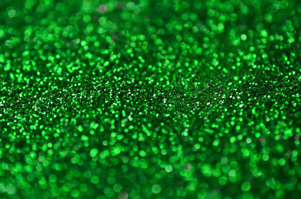 A huge amount of green decorative sequins. Background image with shiny bokeh lights from small elements - Photo, Image