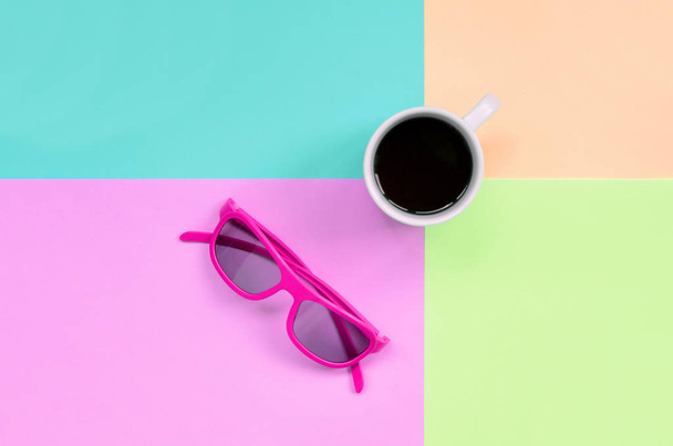 Pequeña taza de café blanco y gafas de sol de color rosa sobre fondo de colores pastel de moda rosa, azul, coral y lima
 - Foto, Imagen