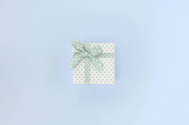 Pequeña caja de regalo blanca con cinta se encuentra sobre un fondo violeta
 - Foto, imagen