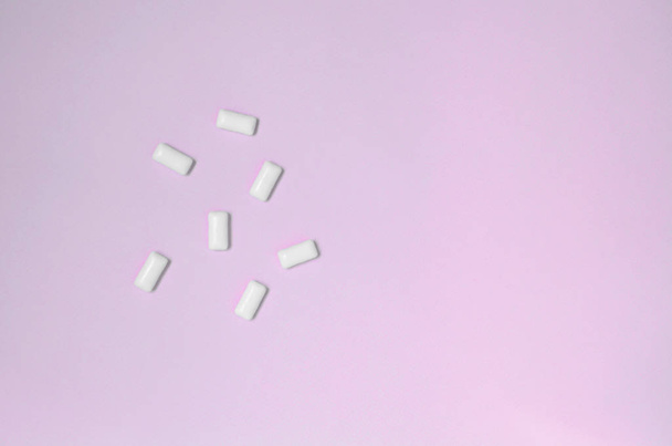 A few chewing gums lie on texture background of fashion pastel pink color paper - Foto, immagini
