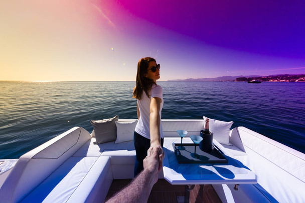 vrouw houdt man's hand op luxe jacht - Foto, afbeelding