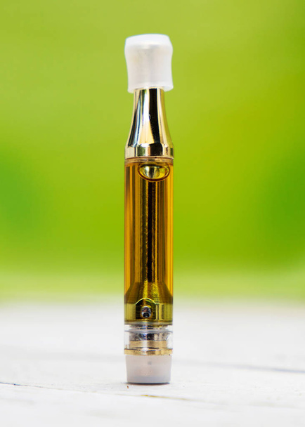 Vape Pen on blurred green background. Vaping Cannabis and Marijuana. - Φωτογραφία, εικόνα