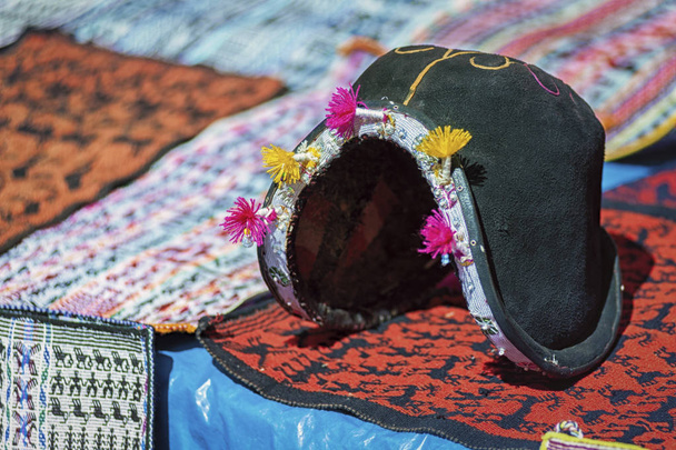 Sombrero de hombre tradicional y tejidos dispuestos en el mercado local del domingo de Tarabuco, Bolivia, América del Sur
 - Foto, Imagen