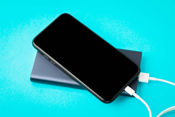 Carga de Smartphone con Power Bank a través de un cable USB en backgr azul
 - Foto, imagen
