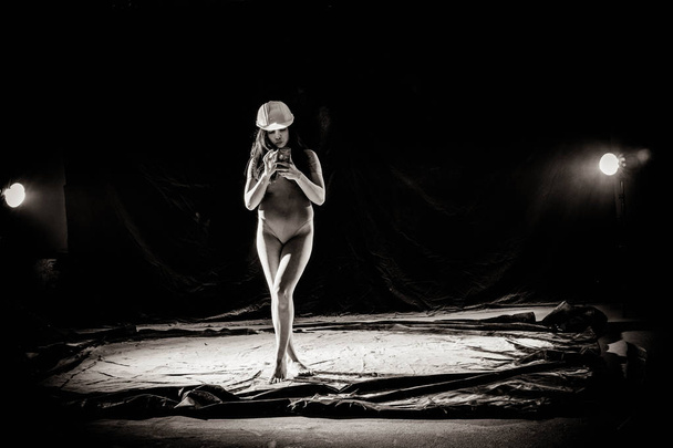 La chica con la harina en el cuerpo estira los brazos con harina tirada sobre fondo negro imagen en blanco y negro
 - Foto, Imagen