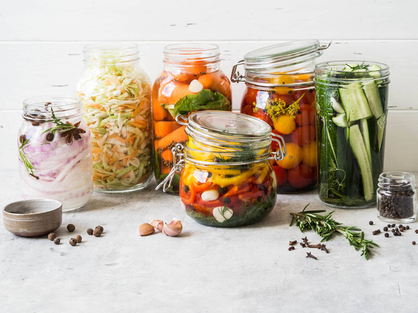 Pickled vegetables. Salting various vegetables in glass jars for long-term storage. Preserves vegetables in glass jars. Variety fermented green vegetables on table - Photo, Image