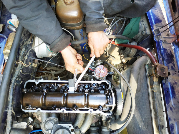 Apretando las válvulas con un auto-iluminador en el garaje en un coche viejo
. - Foto, Imagen