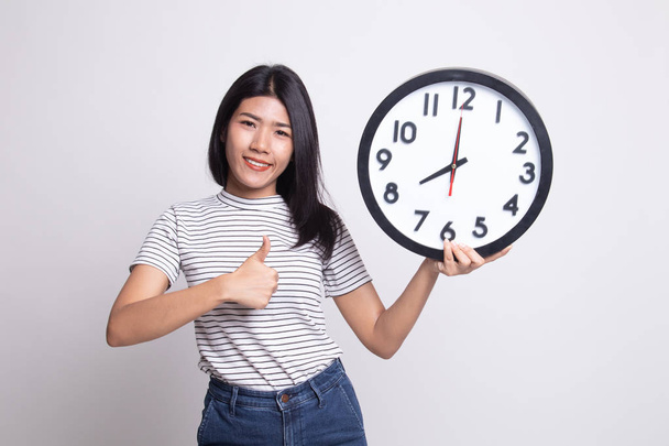 Young Asian woman thumbs up with a clock. - Фото, зображення
