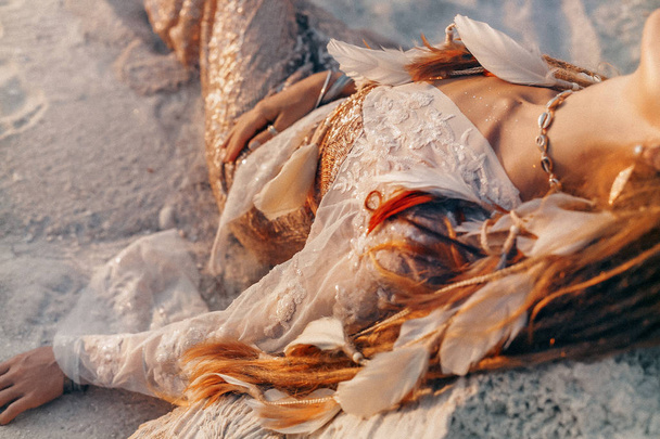 close up of beautiful young woman in elegant dress lying on sand - Foto, Imagem