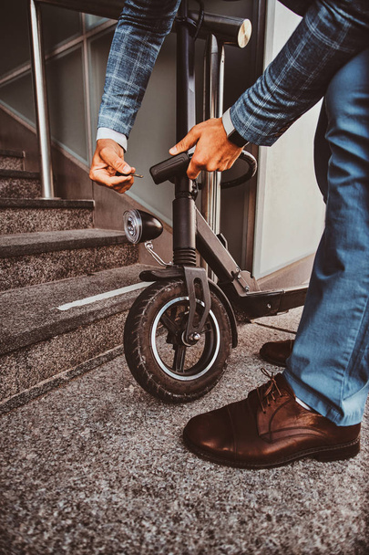 Мужчина паркует свой электро скутер и шкафчик на нем.
 - Фото, изображение