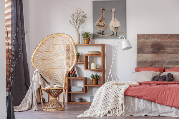 Wicker peacock chair with blanket in comfortable bedroom interior with scandinavian design - Фото, зображення