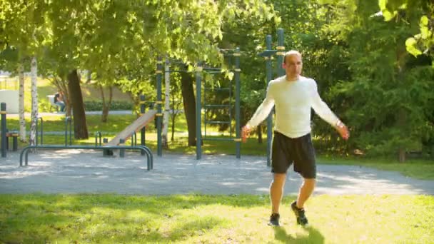 Kulturista pro atletického muže, který provádí zahřátí na zeleném parku - Záběry, video