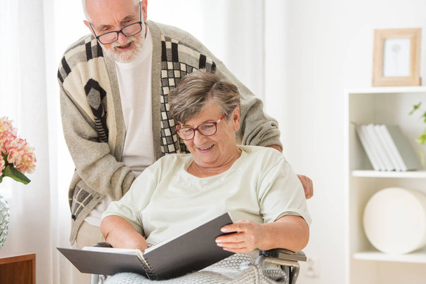 Happy Senior married couple with photo album at nursing home - Фото, изображение