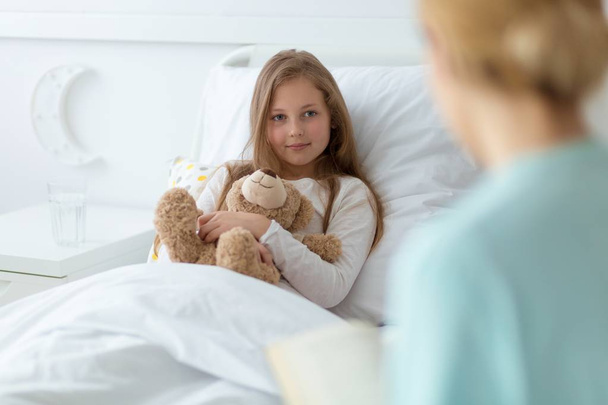 Girl in the hospital holding a teddy bear - Фото, изображение