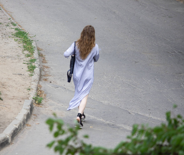 Uma mulher com uma mochila nas costas. Mulher caminha na estrada
 - Foto, Imagem